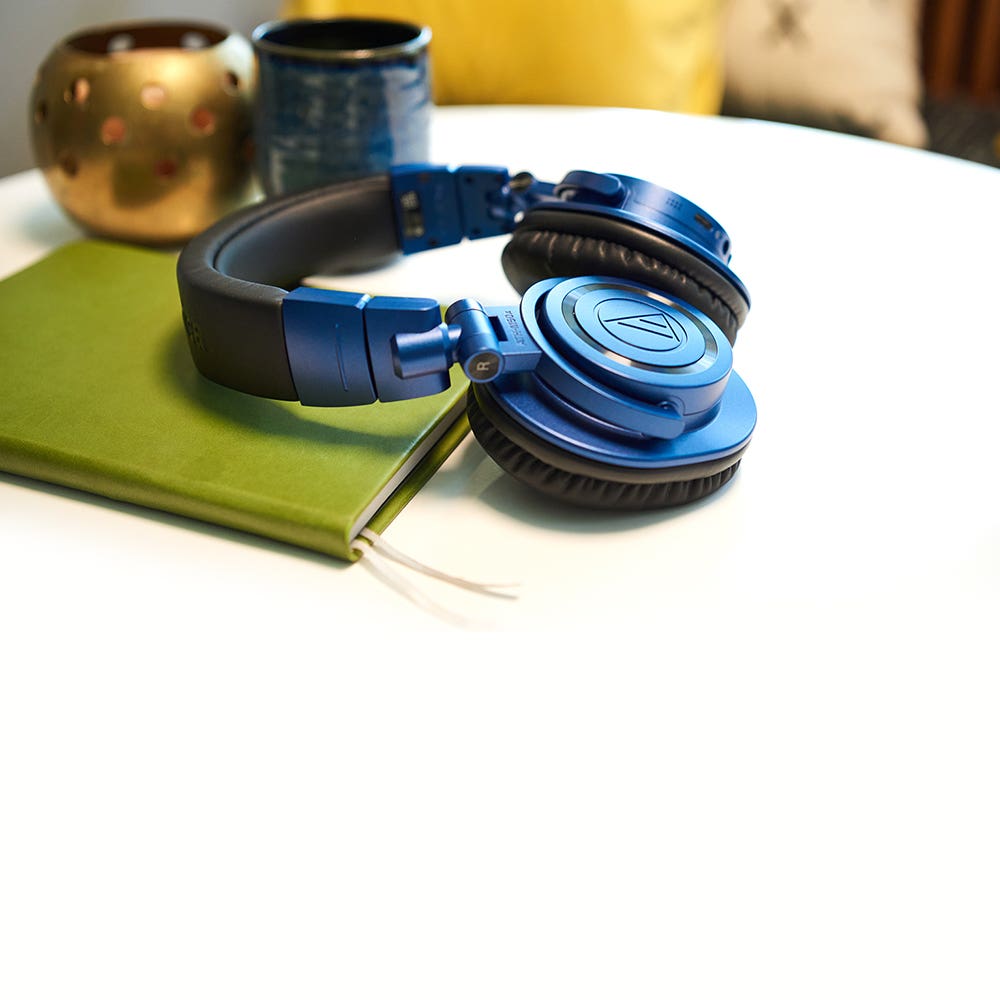 Écouteurs ATH-M50xBT2DS édition limitée bleu profond sur la table avec livre 